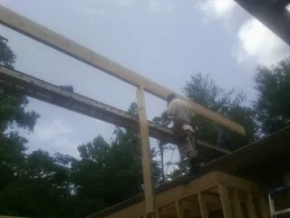 Carpenter setting a ridge beam over a new addition frame — Ice Dam Removal by Roofing Brothers in Lake Hill