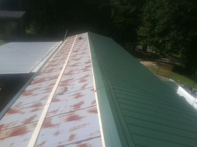 Old rusted panels beside newly installed green metal roofing — Wind Damage Roof Repair by Roofing Brothers in Lake Hill