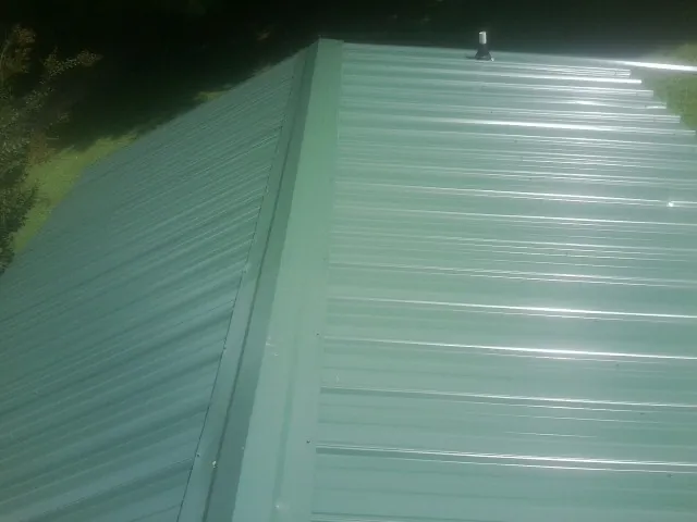 New green metal panels meeting at the ridge of a roof — Flat Roof Repair work by our crew in Lake Hill