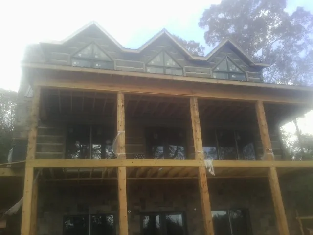 Dormers and porch framing on a large log home under construction — Roof Coating work by our crew in Lake Hill