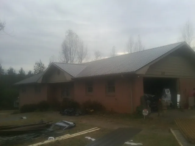 Gray metal roof on a stucco house with an attached garage in Lake Hill