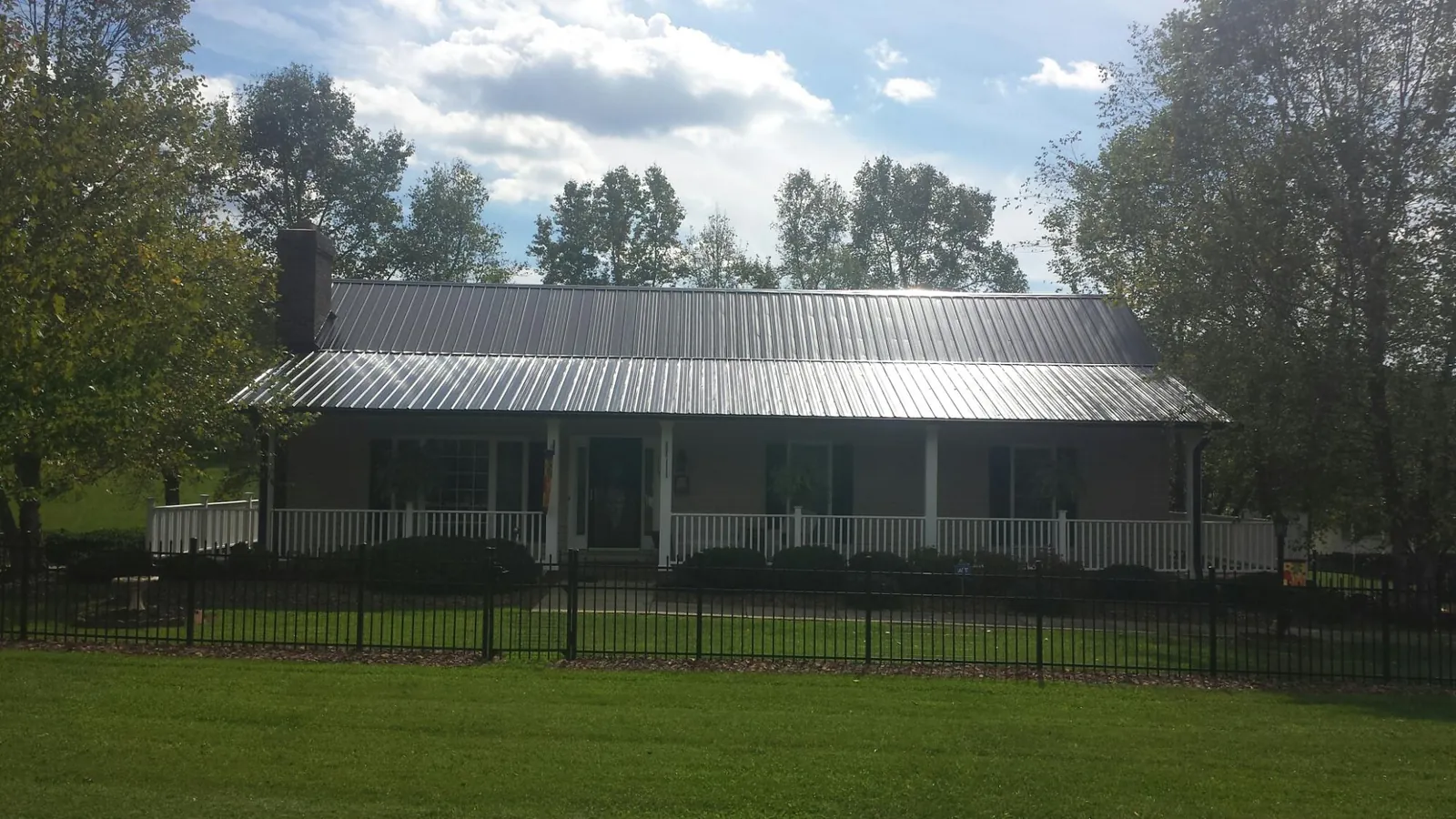 Gray metal roof on a brick ranch with a full width front porch — Gutter Guard Installation work by our crew in Lake Hill