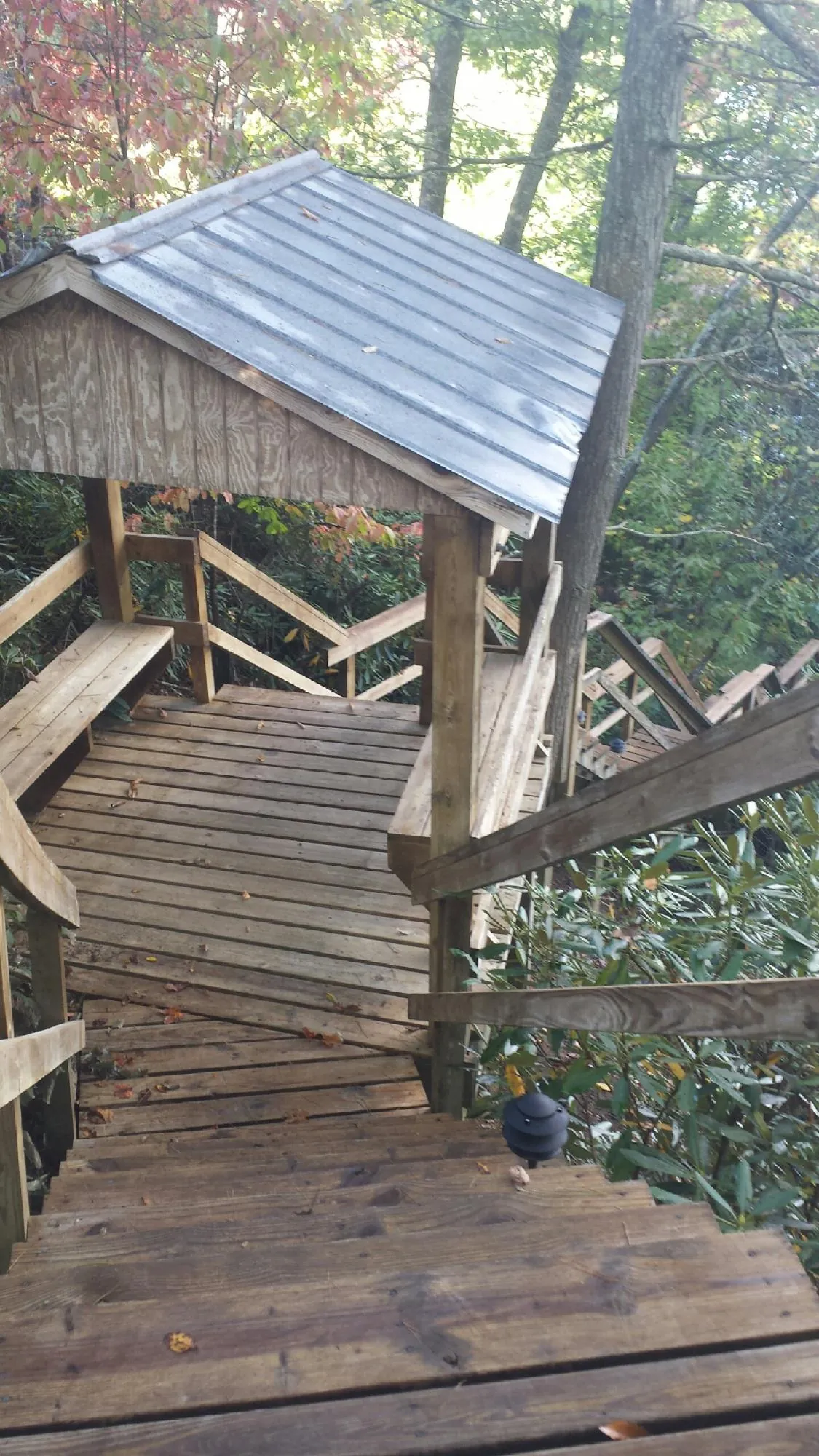 Metal roofed shelter over wooden steps on a wooded walkway — Skylight Repair & Installation work by our crew in Lake Hill