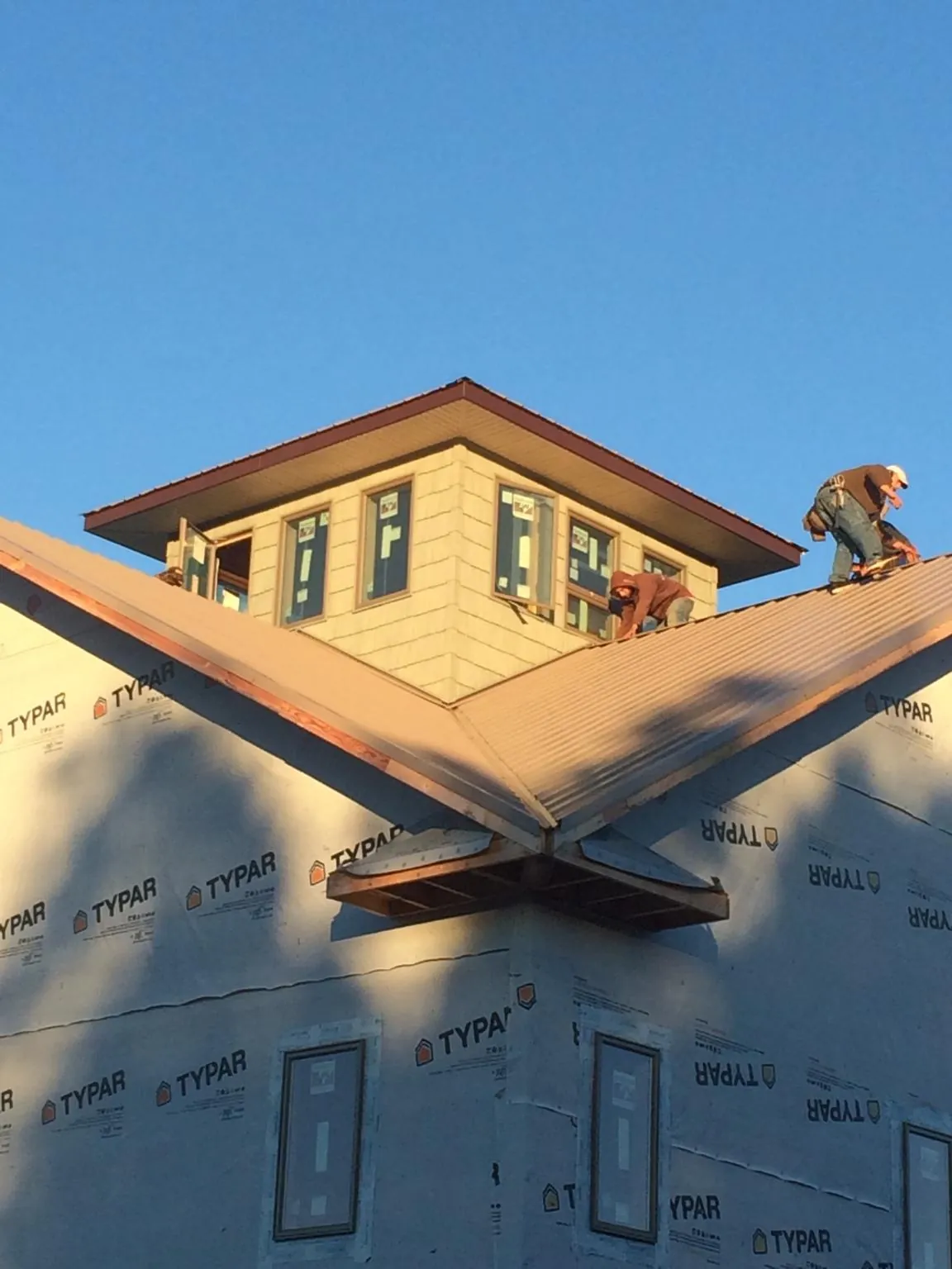 Roofers working around a rooftop cupola on a new metal roof at sunset — Roof Waterproofing in Lake Hill by Roofing Brothers